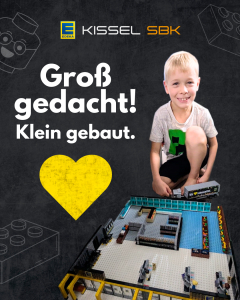 Ein Junge kniet lächelnd neben einem detailreich nachgebauten EDEKA Kissel Markt aus LEGO-Steinen. Über ihm steht der Slogan "Groß gedacht! Klein gebaut." auf dunklem Hintergrund mit LEGO-Design-Elementen. Links oben ist das EDEKA Kissel SBK-Logo zu sehen, darunter ein großes gelbes Herz. Der LEGO-Markt zeigt Regale, Kassenbereiche, eine Obst- und Gemüseabteilung sowie einen EDEKA-LKW mit dem Schriftzug „Wir ♥ Lebensmittel“