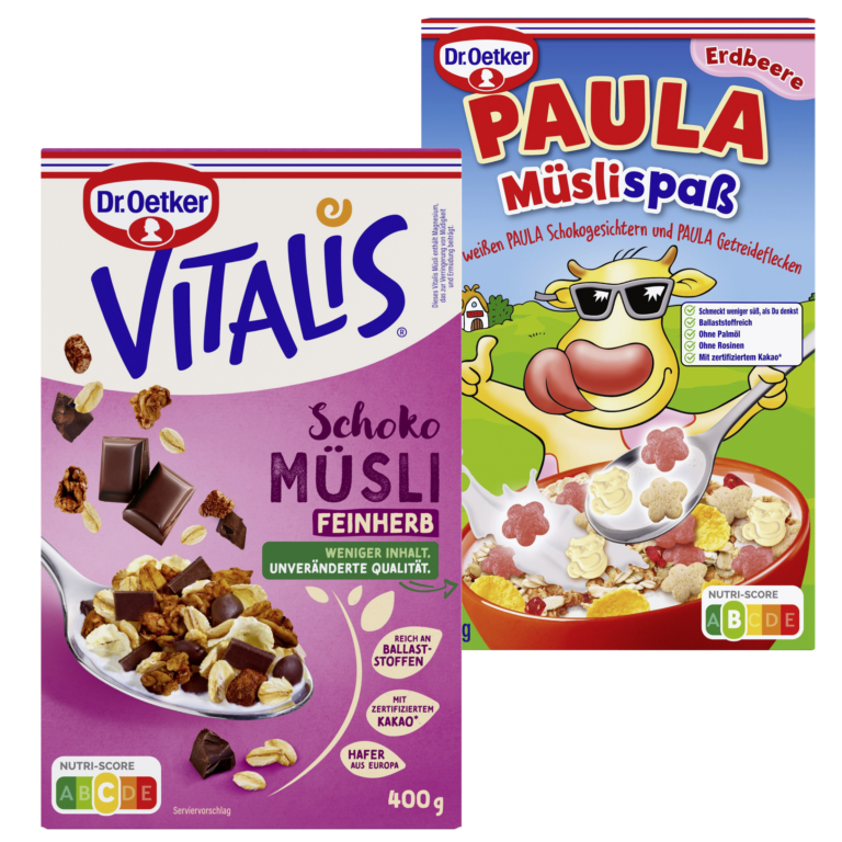 Zwei Müslipackungen von Dr. Oetker. Links „Vitalis Schoko Müsli Feinherb“ mit dunkler Schokolade, Haferflocken und Nüssen, 400g-Packung in Lila. Rechts „PAULA Müslispaß Erdbeere“ mit bunten Getreidefiguren und Erdbeer-Geschmack, kindlich gestaltet mit Kuh-Maskottchen auf der Verpackung.