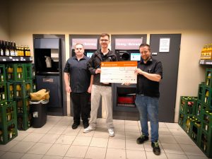 Zu sehen ist eine Fotografie von der Spendenübergabe im EDEKA Kissel SBK Kandel an das Jugendzentrum Kandel. Auf dem Bild zu sehen ein Mitarbeiter des Marktes und zwei Mitarbeiter der Jugendzentrums. Zwei der Männer halten zusammen einen Sparkassen Check in Höhe von 700€ Richtung Kamera.